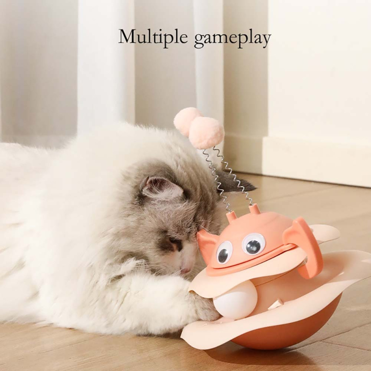 Un gatto gioca con un giocattolo. Il giocattolo ha la forma di un granchio e ha una palla all'interno. Il gatto è bianco e grigio.