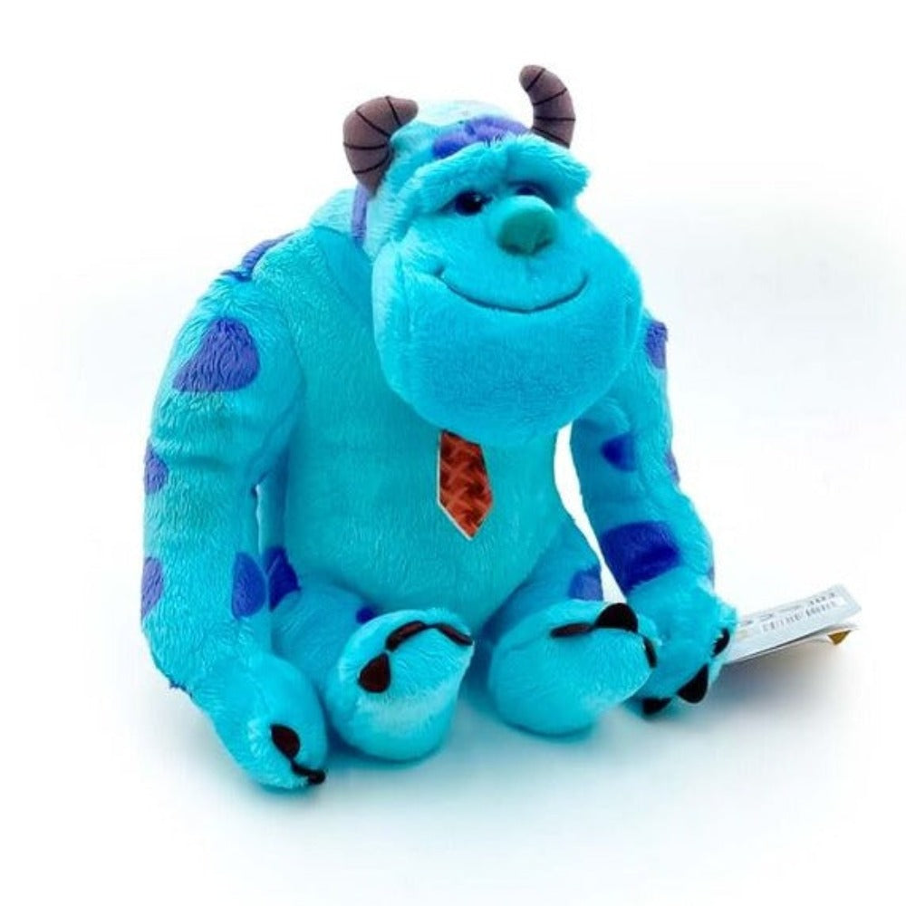 Ein blaues, plüschiges Sully-Spielzeug aus Monster AG mit lila Flecken und einer roten Krawatte, das auf einer weißen Oberfläche sitzt.