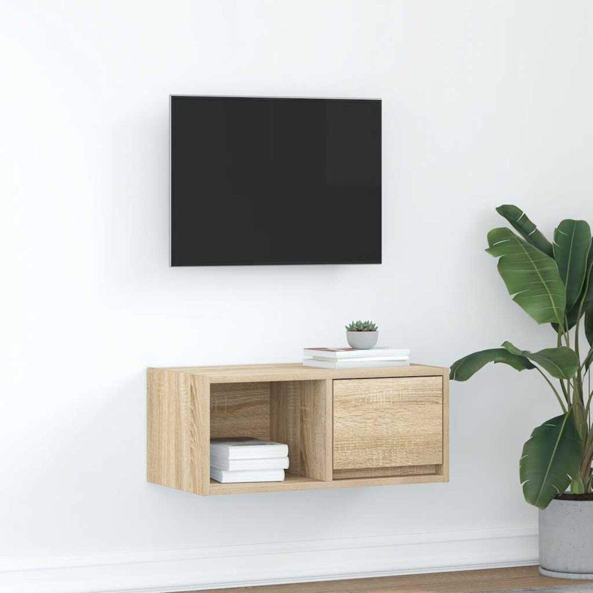 Ein an der Wand montierter Fernseher über einem schwebenden Holzschrank mit Büchern und einer kleinen Pflanze. Rechts eine große Topfpflanze.
