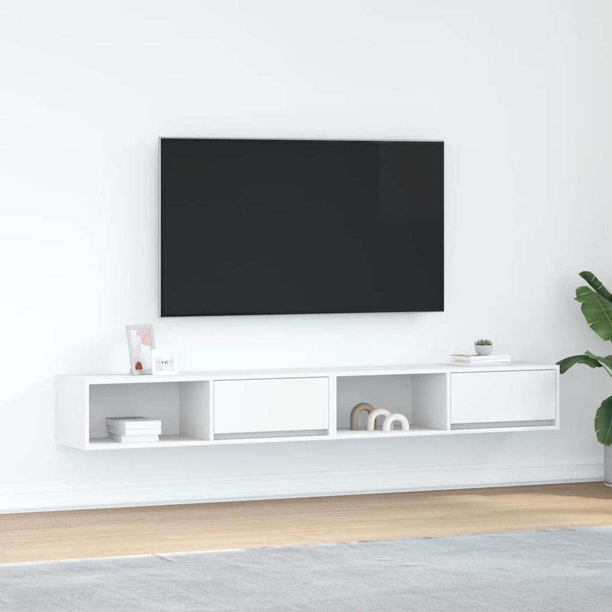 Ein an der Wand montierter Fernseher über einem weißen Schrank. Der Schrank hat offene Regale und Schubladen. Rechts ist eine Pflanze.