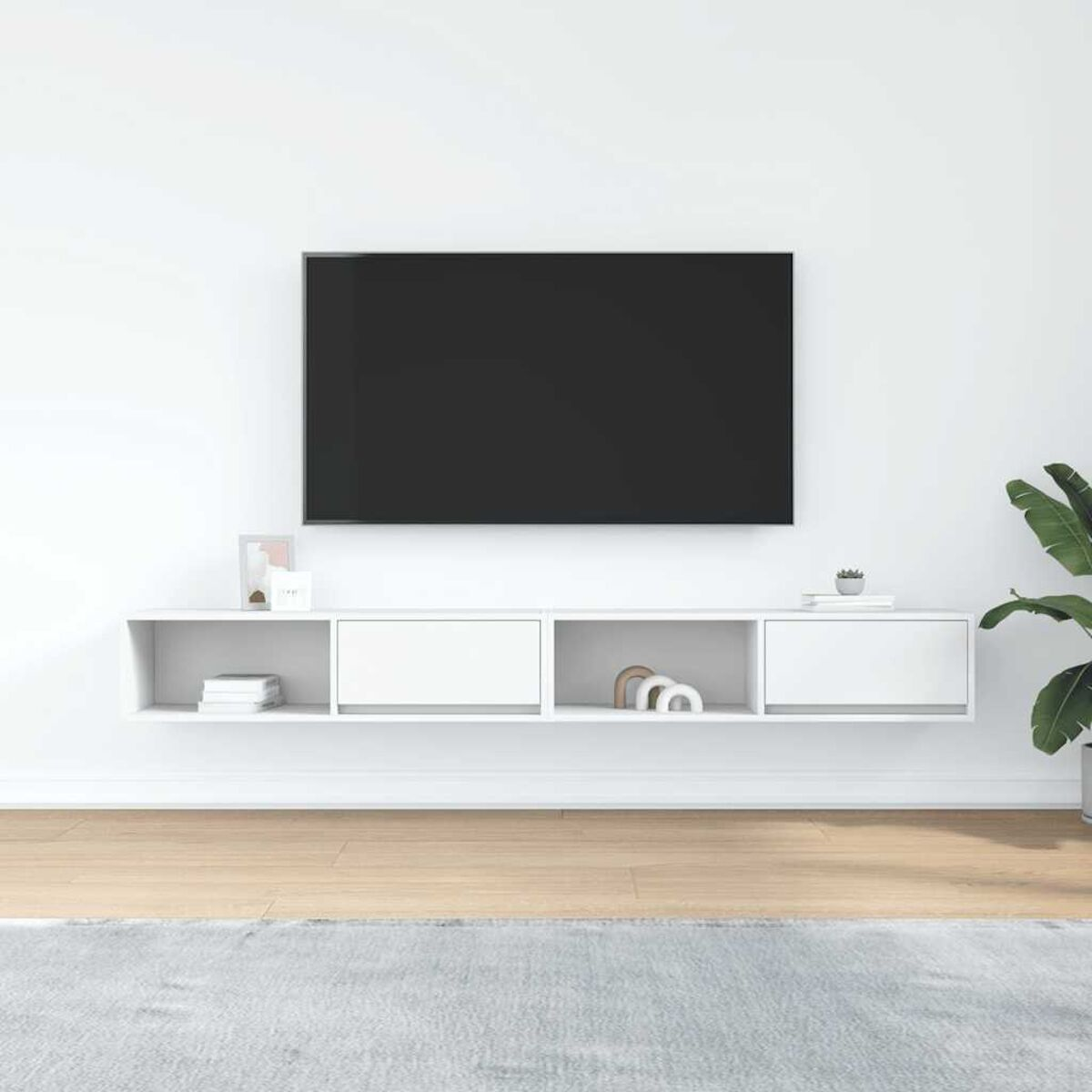 Modernes Wohnzimmer mit Wand-TV über weißem Schrank. Zubehör auf dem Schrank und eine Pflanze rechts.