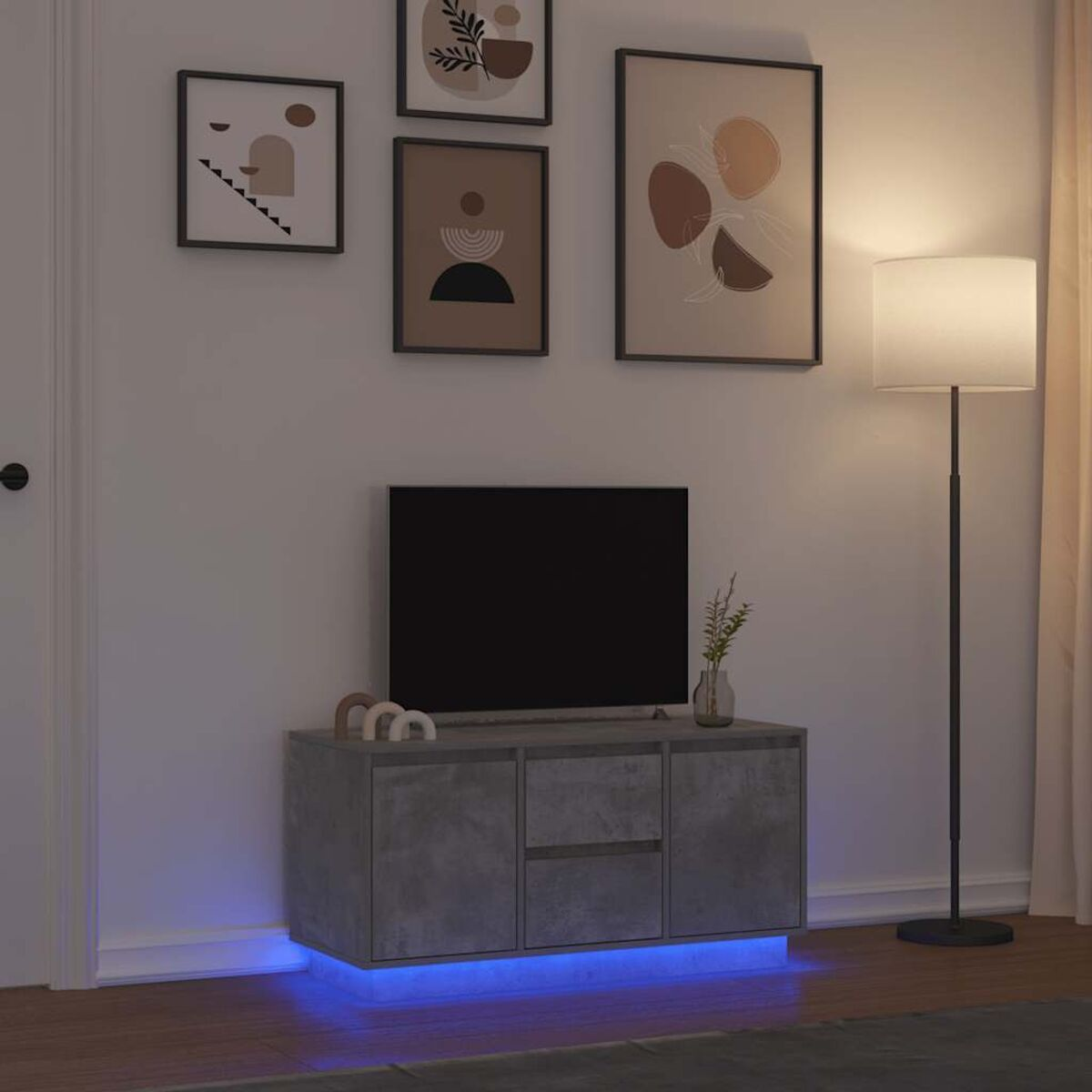 Ein modernes Wohnzimmer mit einem Fernseher auf einem grauen Schrank, darunter blaue LED-Leuchten. Kunst und eine Lampe vervollständigen die Szene.