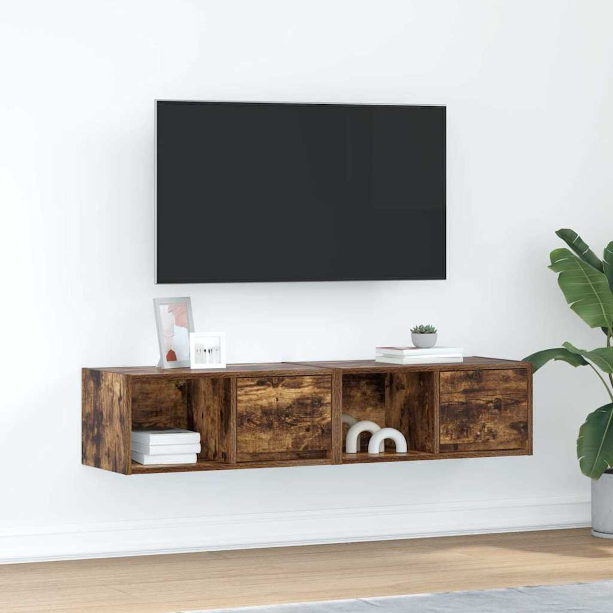Ein montierter Holzschrank mit einem Fernseher darüber. Bücher, Bilderrahmen und eine Pflanze stehen auf dem Schrank. Eine Pflanze ist im Hintergrund.
