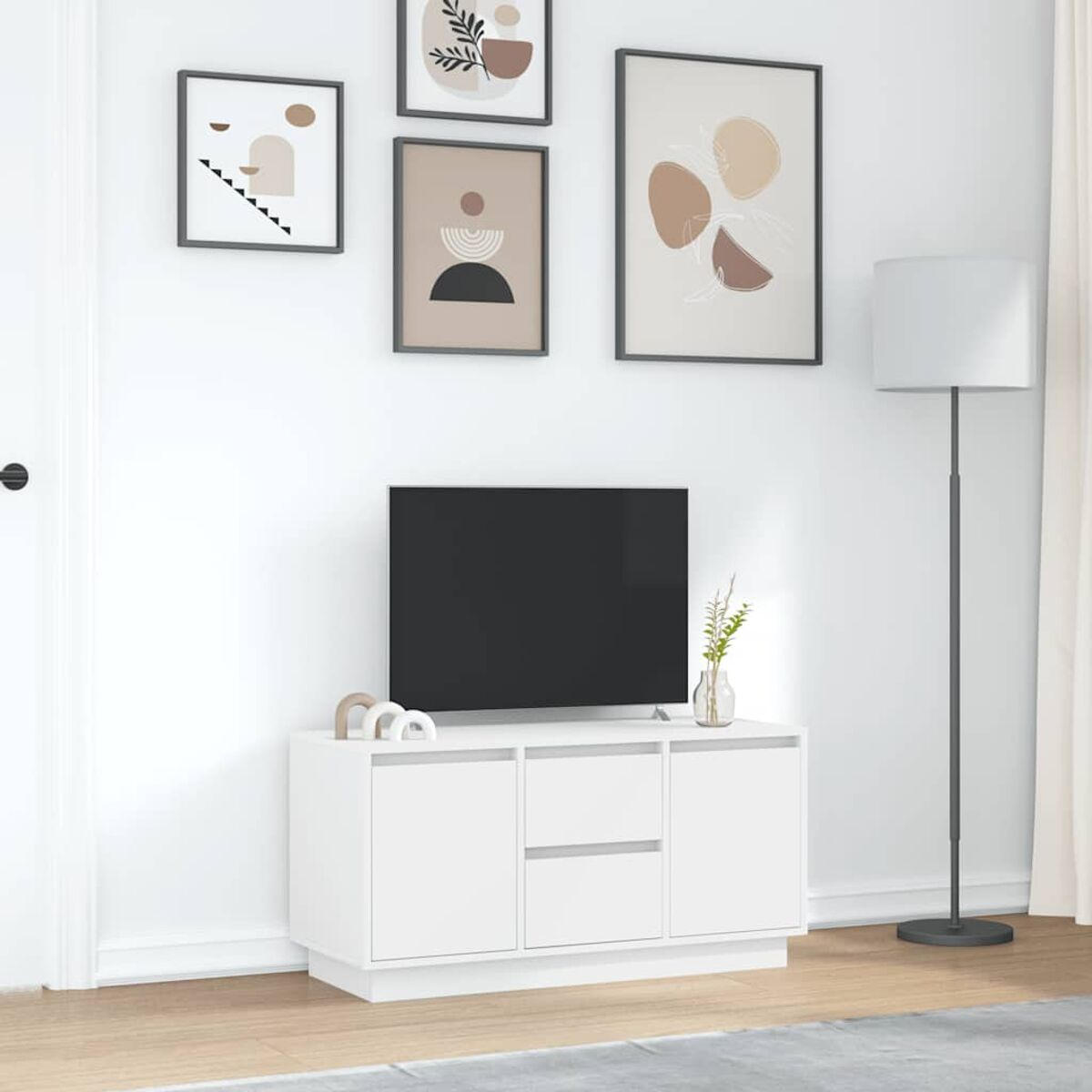 Weißer TV-Ständer mit Fernseher, Kunst und Lampe. Wandkunst darüber. Vase und Dekor auf dem Ständer. Grauer Teppich auf dem Boden.