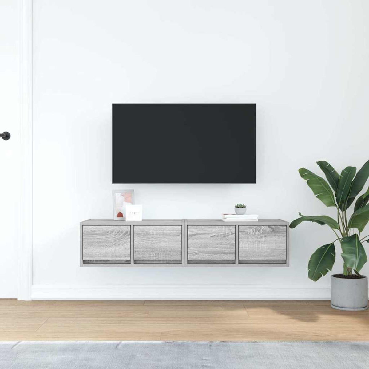 Ein modernes Wohnzimmer mit Wand-TV, grauem Schrank, Topfpflanze und Holzboden vor weißer Wand.