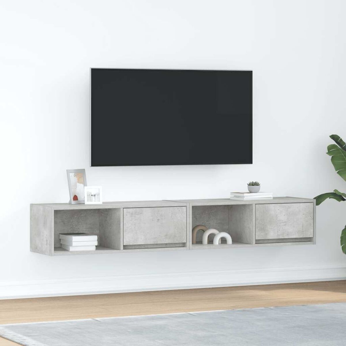 Ein modernes Wohnzimmer mit einem grauen TV-Ständer, einem Flachbildfernseher an der Wand und einer Pflanze.