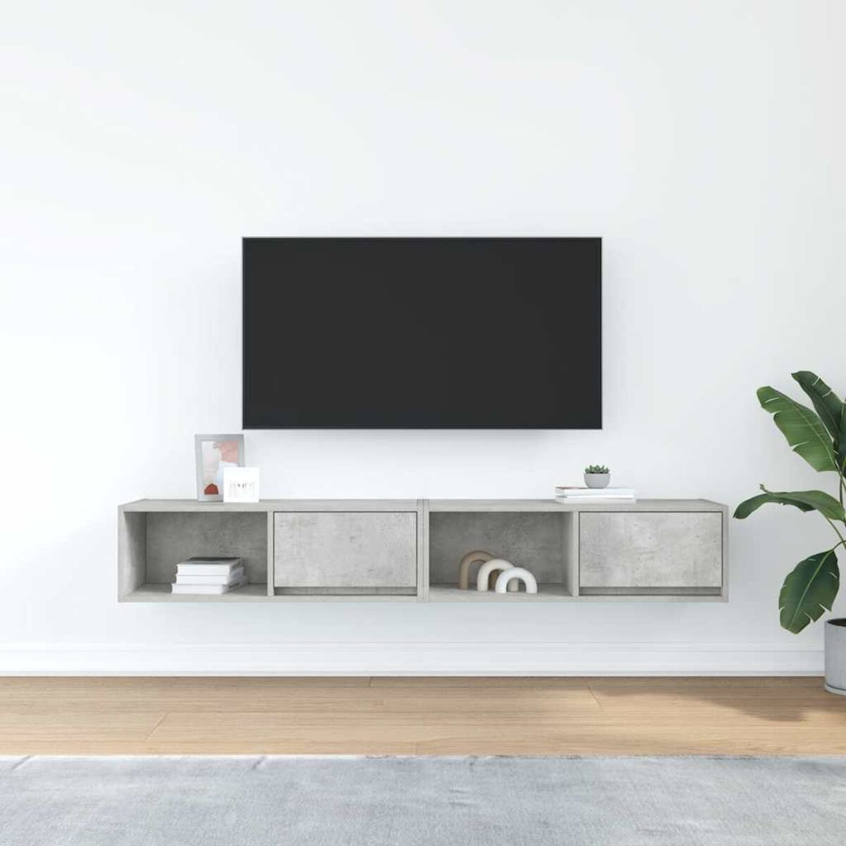 Modernes Wohnzimmer mit Fernseher über einem grauen Schrank. Rechts eine Pflanze. Der Raum hat Holzböden und einen grauen Teppich.
