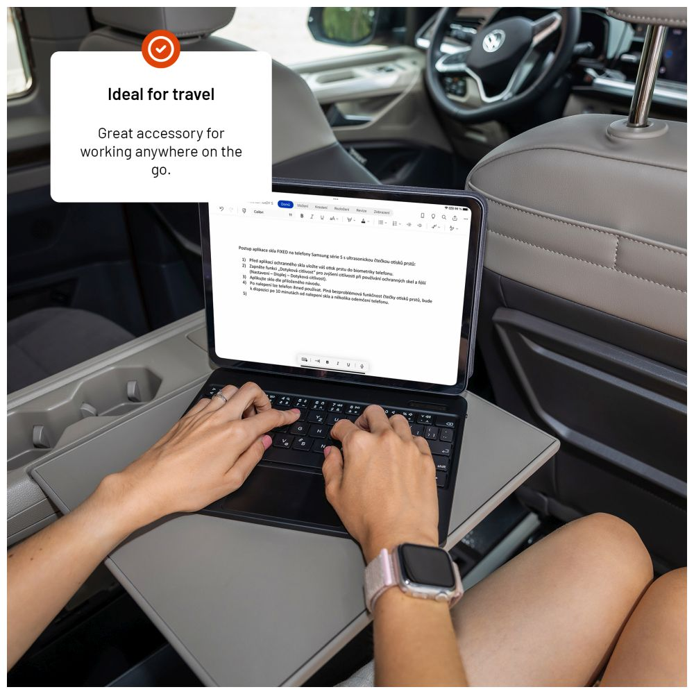 Im Inneren eines Autos tippt eine Person auf einem Tablet mit Tastatur. Auf dem Bildschirm wird Text in einem Dokument angezeigt.
