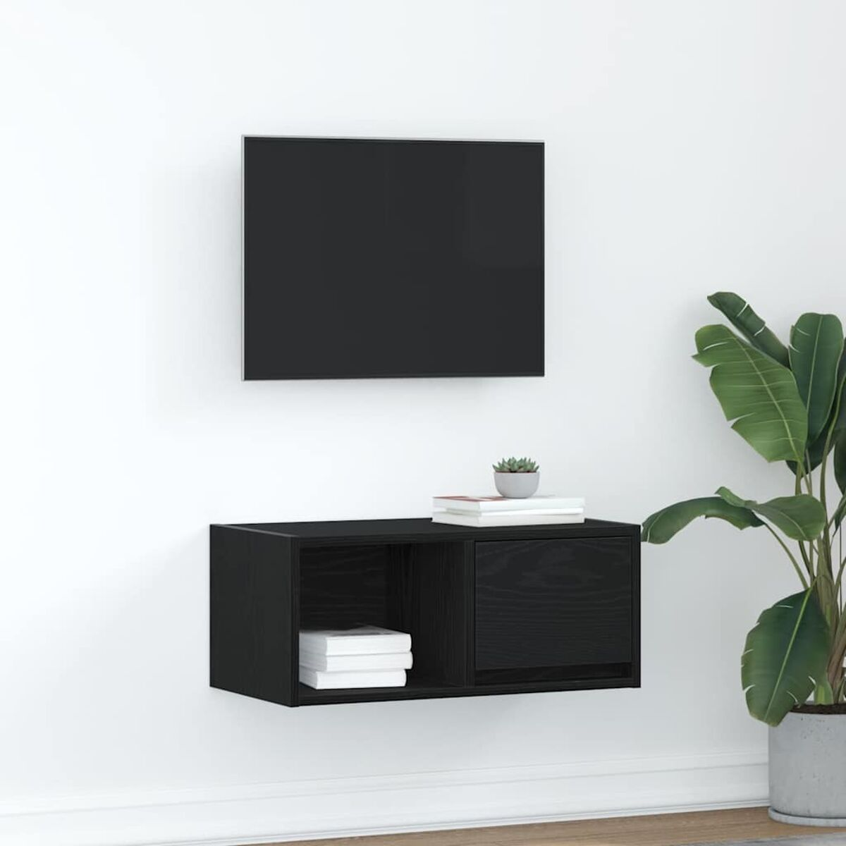 Ein schwarzer Fernseher und ein schwarzer, an der Wand befestigter Schrank mit Büchern und Pflanzen stehen vor einer weißen Wand.