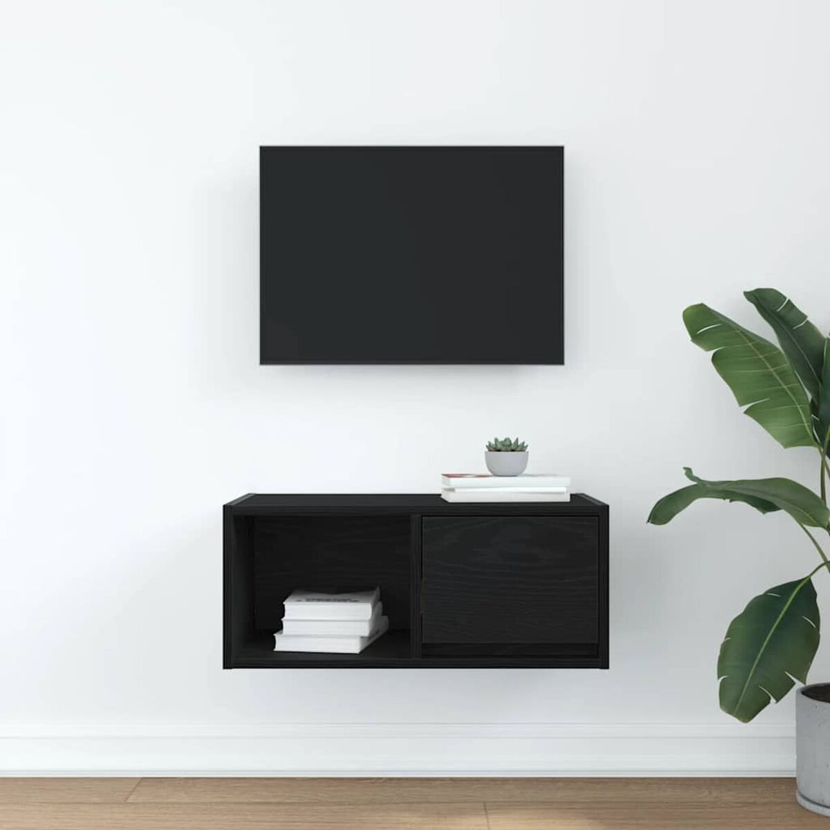 Ein schwarzer, an der Wand befestigter Schrank mit Büchern und einer Pflanze. Rechts eine große grüne Pflanze. Oben ein schwarzes Rechteck.