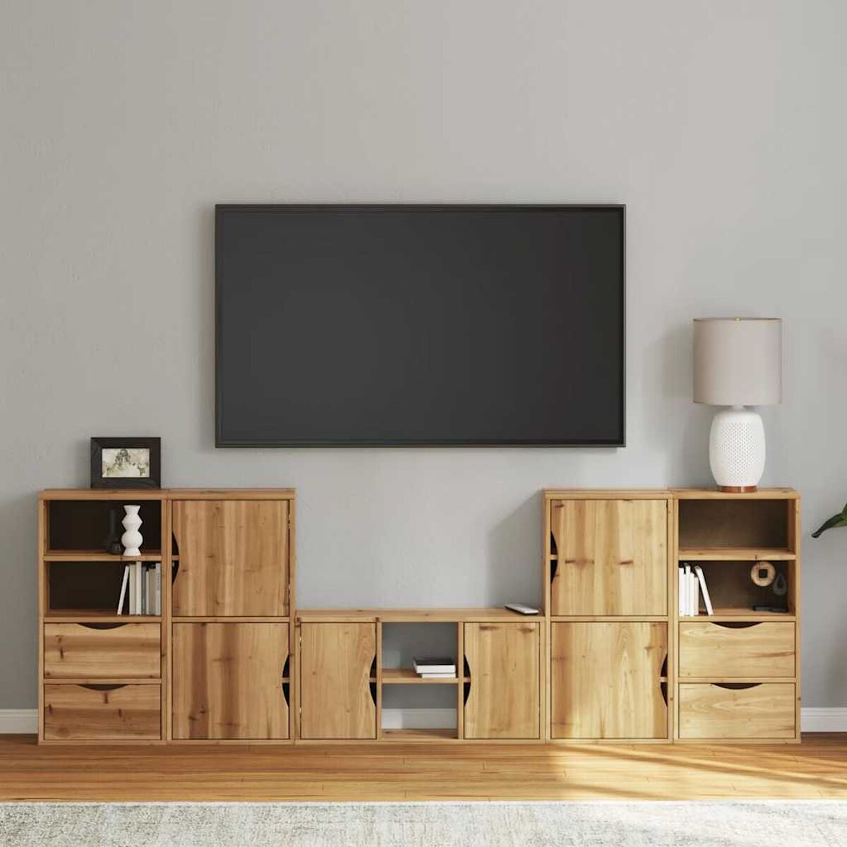 Ein Wohnzimmer mit Holzschränken, Fernseher und Lampe. Die Wand ist grau. Der Boden ist aus Holz.