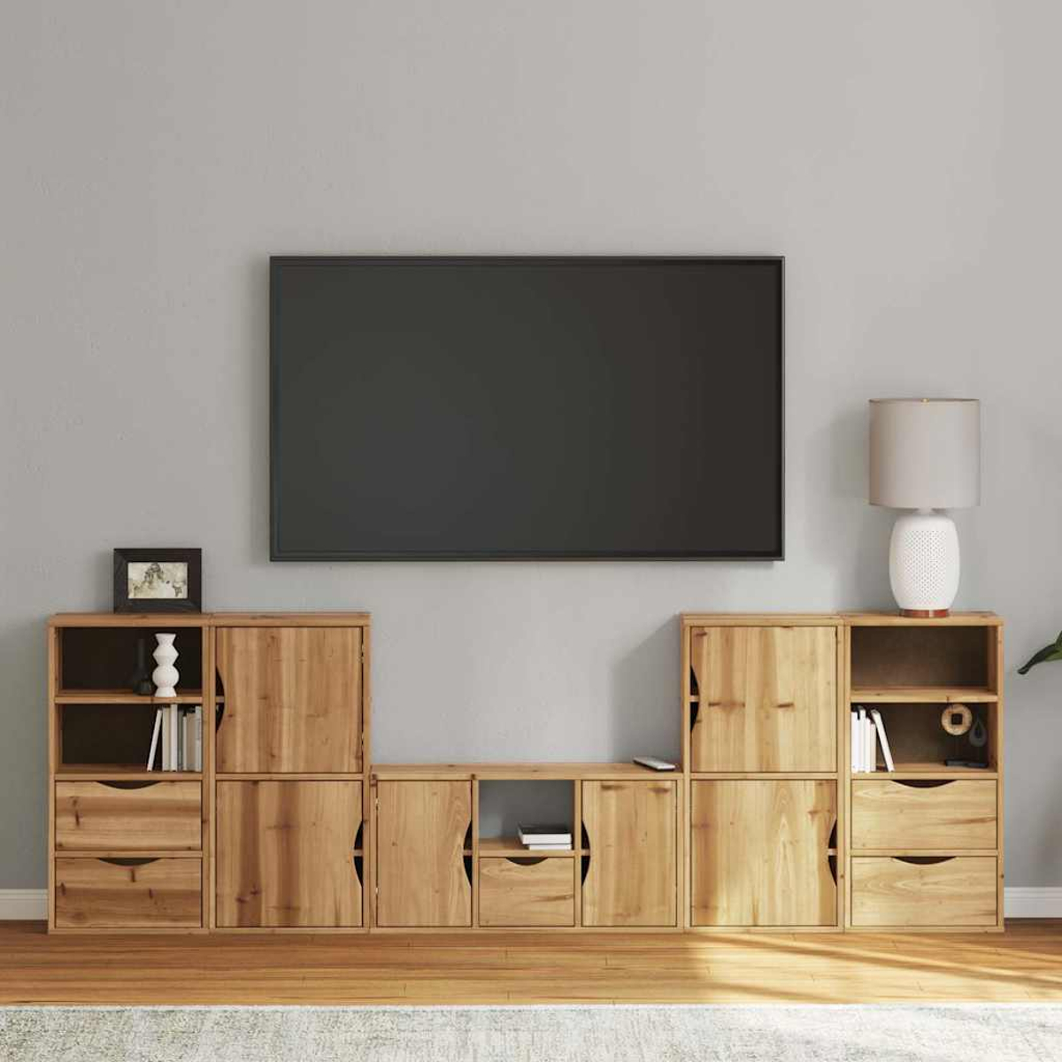 Ein Unterhaltungscenter aus Holz mit einem Fernseher darüber. Das Center hat Schränke, Schubladen und offene Regale. Eine Lampe und Dekoration sind sichtbar.