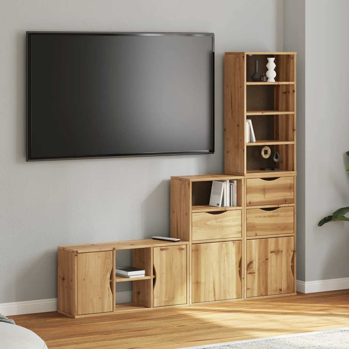 Ein Wohnzimmer mit Holzmöbeln und einem großen Fernseher. Es gibt Regale, Schubladen und einen Schrank, alles in hellem Holz.