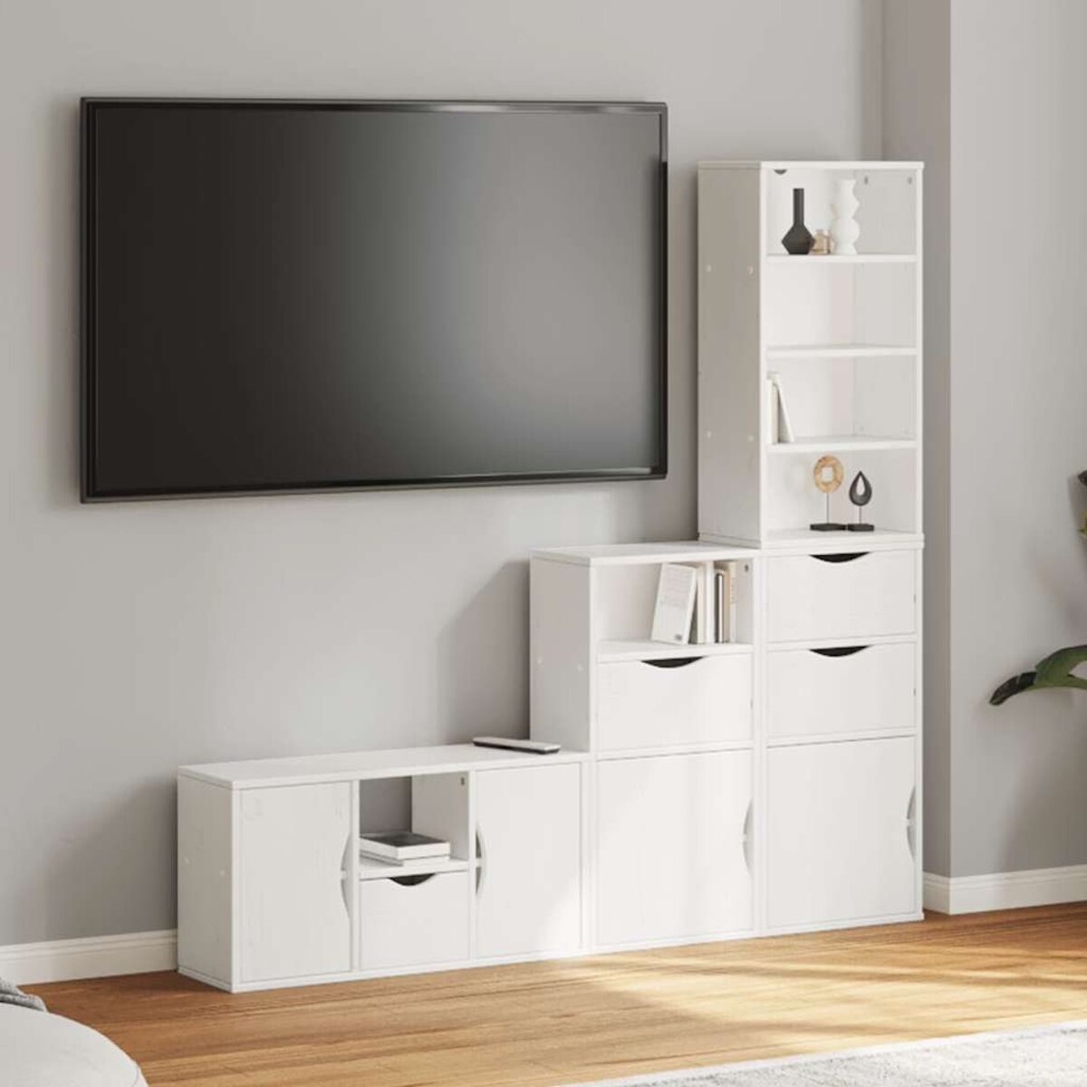 Ein großer schwarzer Fernseher hängt über weißen Aufbewahrungsschränken. Rechts befindet sich ein weißes Regal. Holzboden.