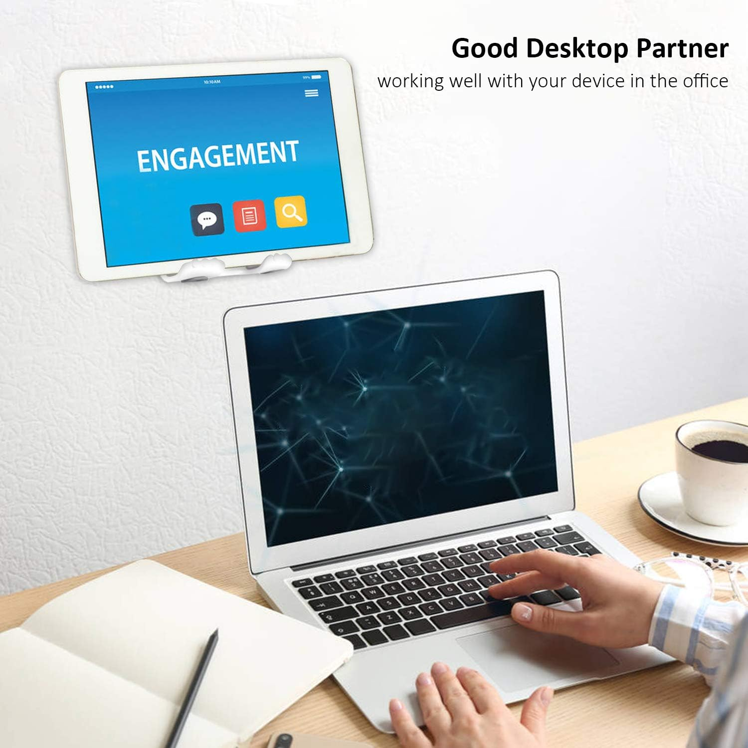 Eine Person benutzt einen Laptop. Ein Tablet mit dem Wort 'ENGAGEMENT' ist an der Wand befestigt. Eine Tasse Kaffee und ein Notizbuch sind auf dem Schreibtisch.