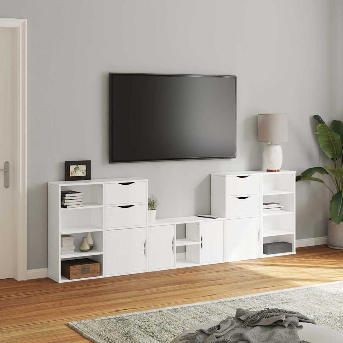 Ein modernes Wohnzimmer mit Fernseher, weißen Schränken, einer Lampe und einer Pflanze. Holzboden und graue Wand. Ein Bilderrahmen steht auf dem Schrank.