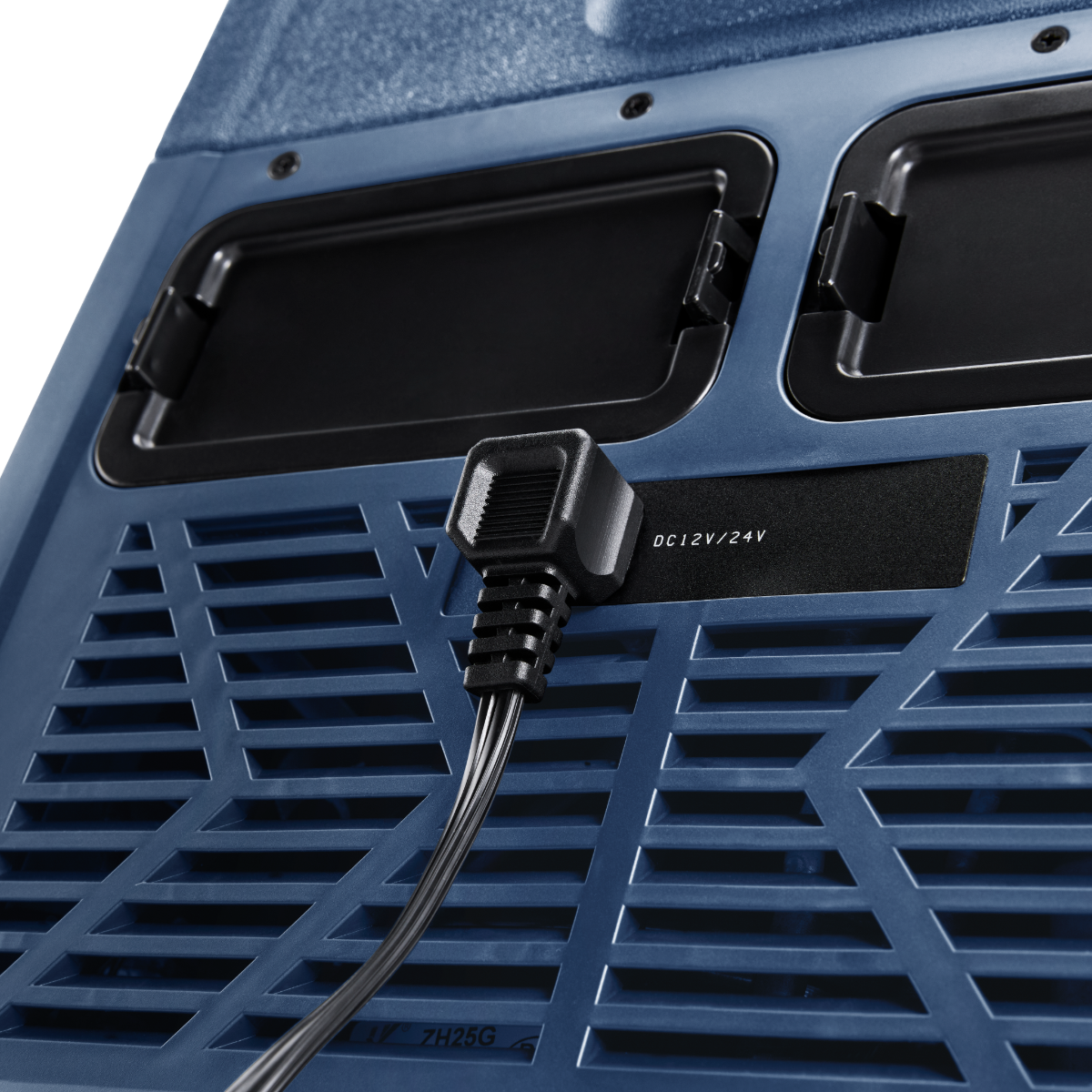 Primo piano di un refrigeratore blu con un cavo di alimentazione nero collegato. Il refrigeratore ha prese d'aria e un'etichetta che dice DC 12V/24V.