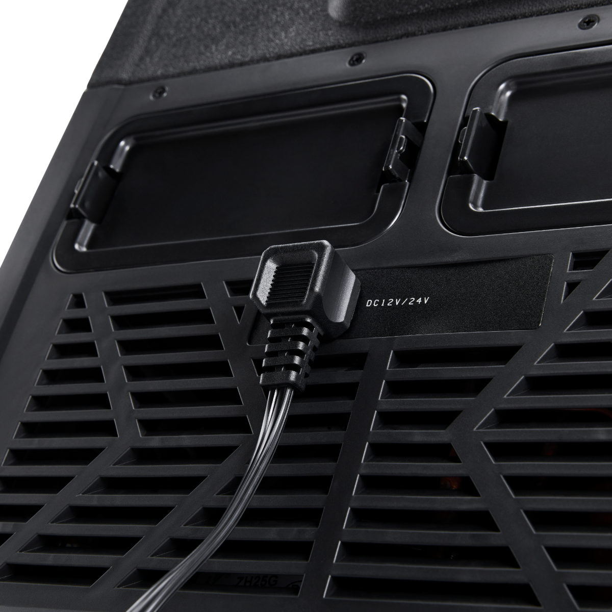Primo piano della parte posteriore di un dispositivo nero. Un cavo di alimentazione è collegato. Sono visibili griglie di ventilazione e un'etichetta 'DC 12V/24V'.