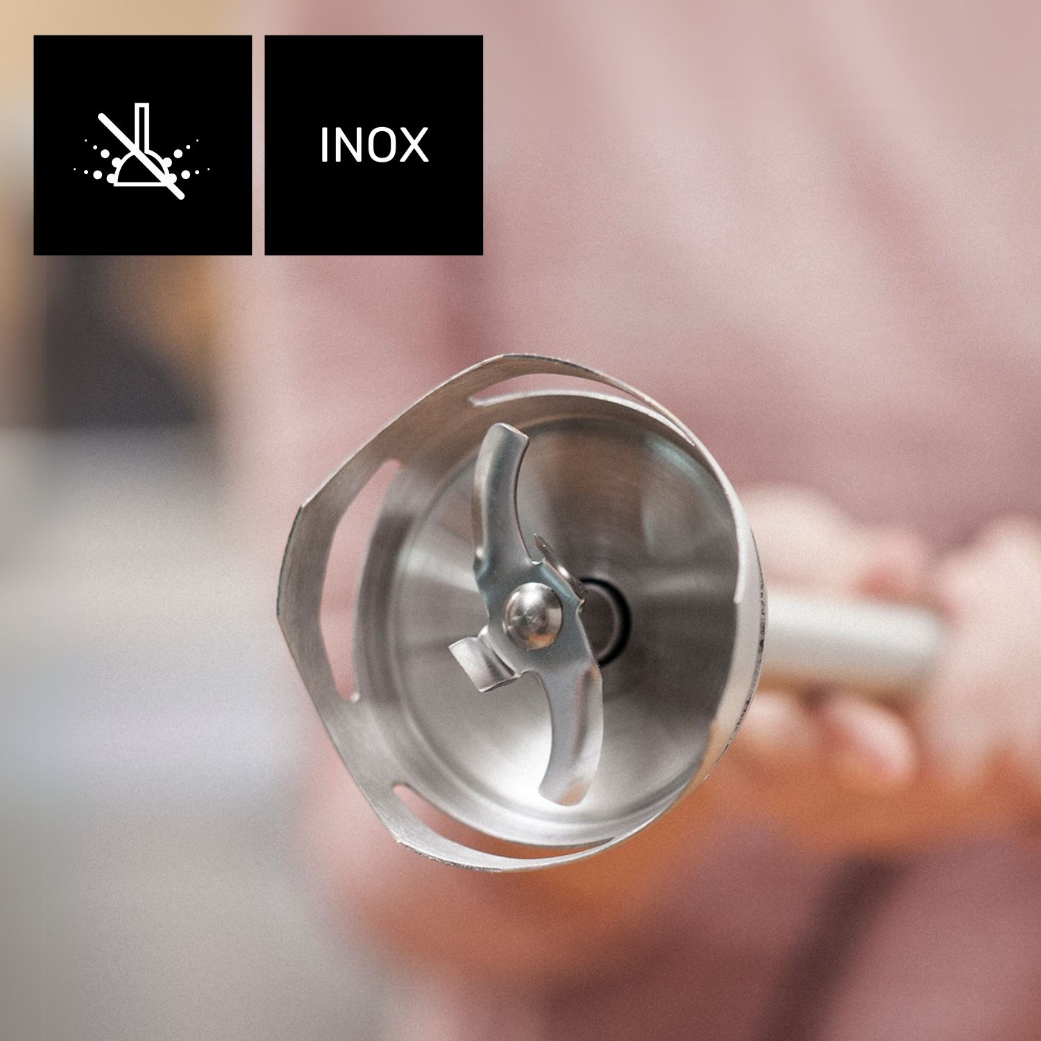 Primer plano de un cabezal de licuadora con cuchillas. Cuadrados negros con iconos blancos y la palabra 'INOX' en el fondo.