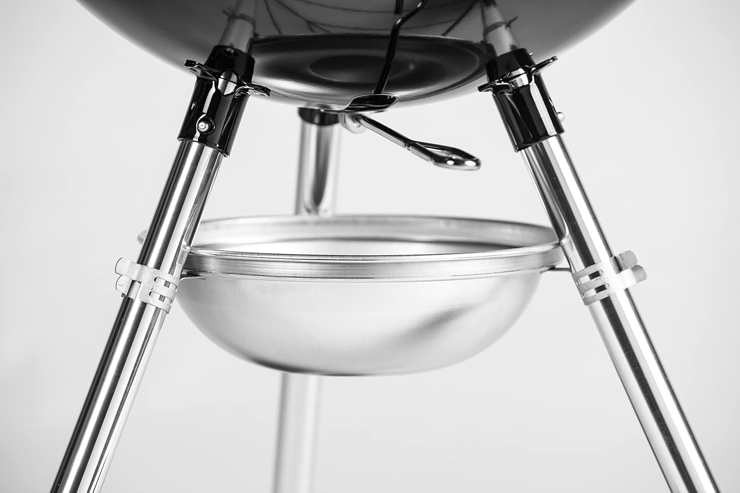 Primo piano di una griglia nera e argento. Le gambe e la ciotola sono argentate. Il coperchio della griglia è nero e si vede una maniglia.
