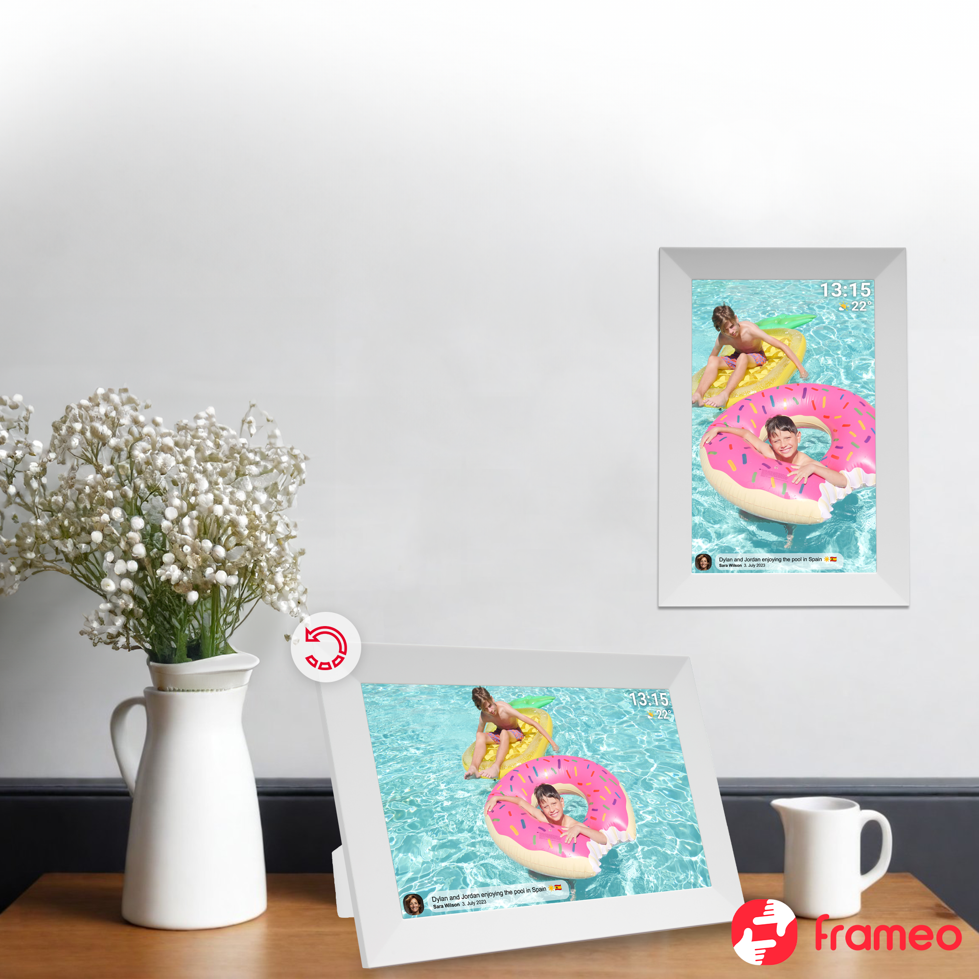 Dwie cyfrowe ramki na zdjęcia wyświetlają scenę basenową z dwoma chłopcami na pontonach. Wazon z kwiatami i dzbanek na stole.