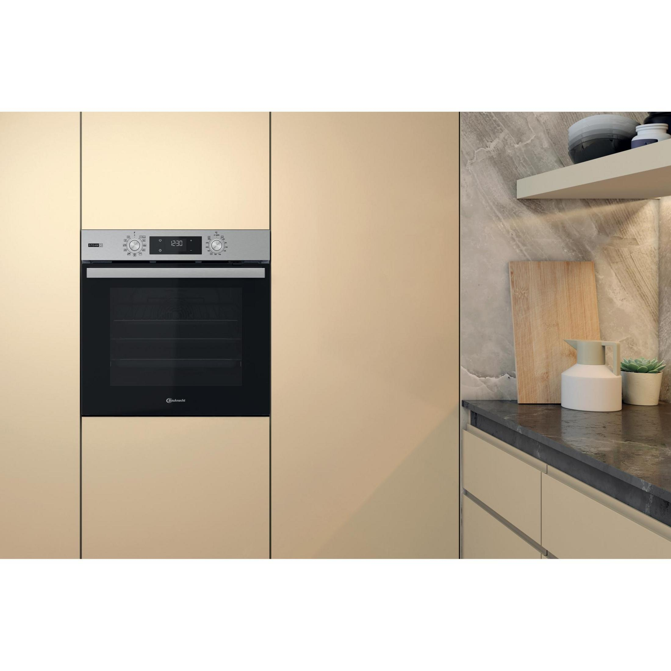 Küchenszene mit Backofen, Schränken und Arbeitsplatte mit Schneidebrett, Vase und Pflanze.