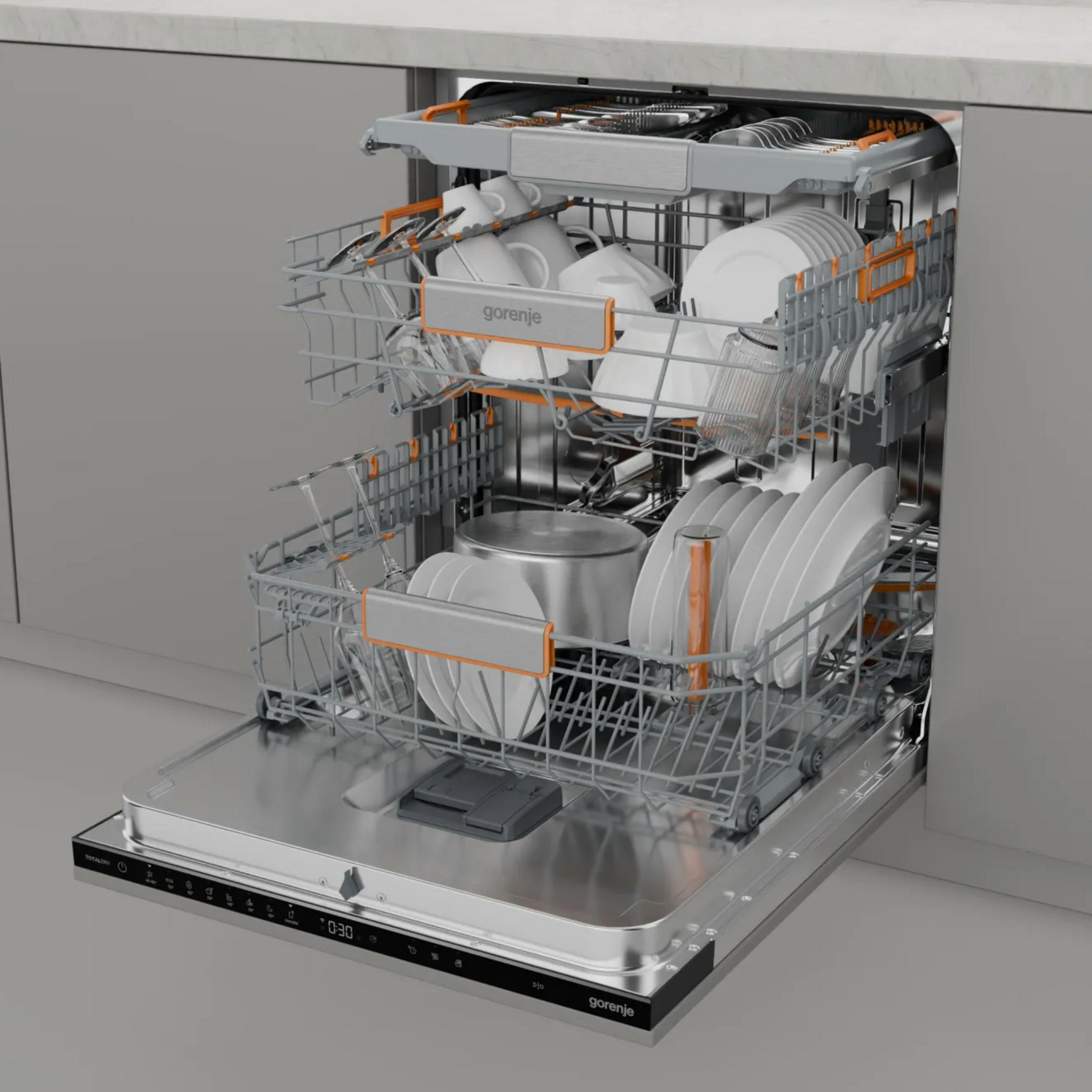Otwarta zmywarka z talerzami, kubkami i sztućcami w środku. Urządzenie ma wnętrze ze stali nierdzewnej i znajduje się w kuchni.