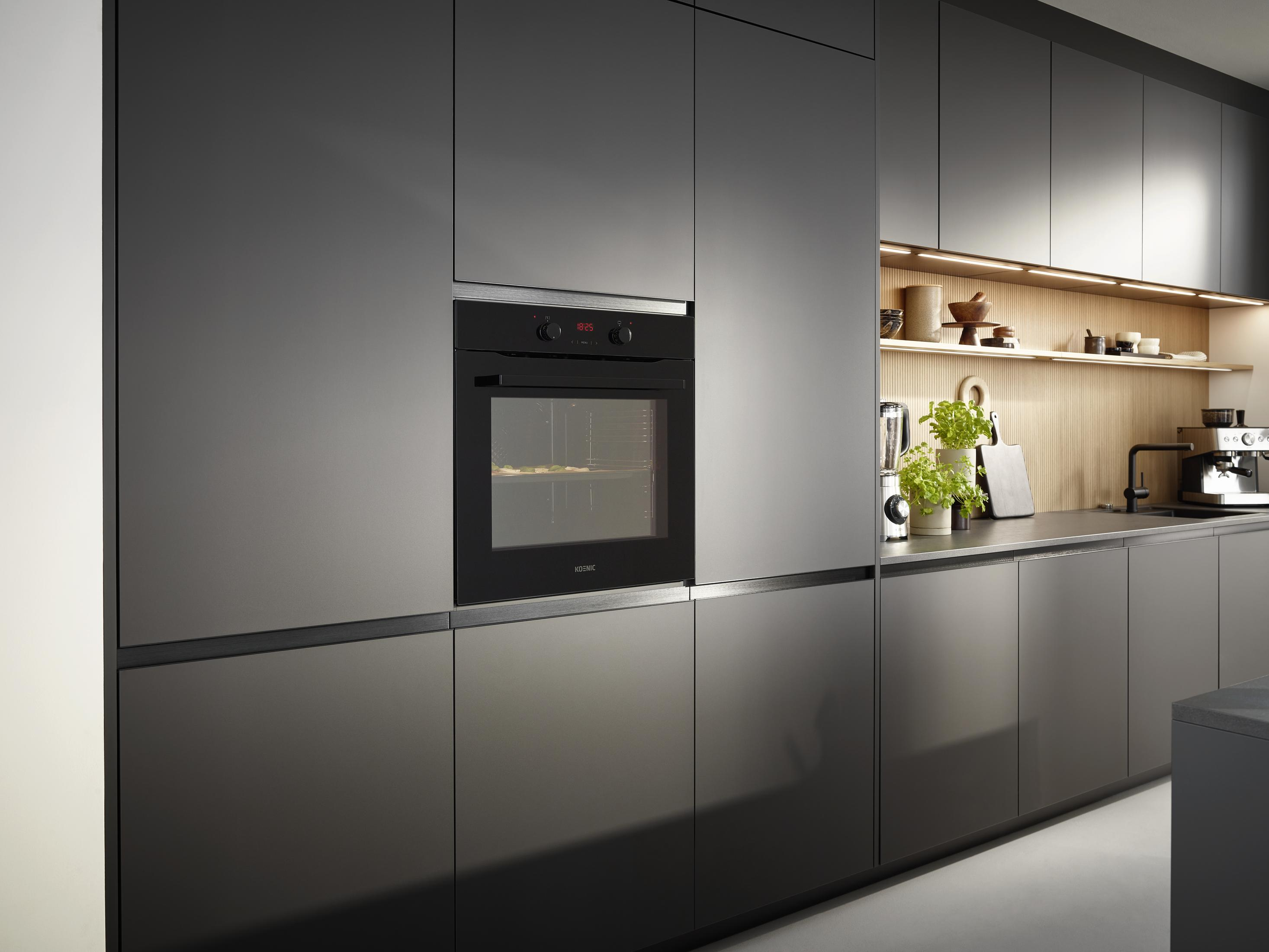 Moderne Küche mit grauen Schränken, Einbaubackofen, Holzregalen und Arbeitsplatte mit Pflanzen und Geräten.