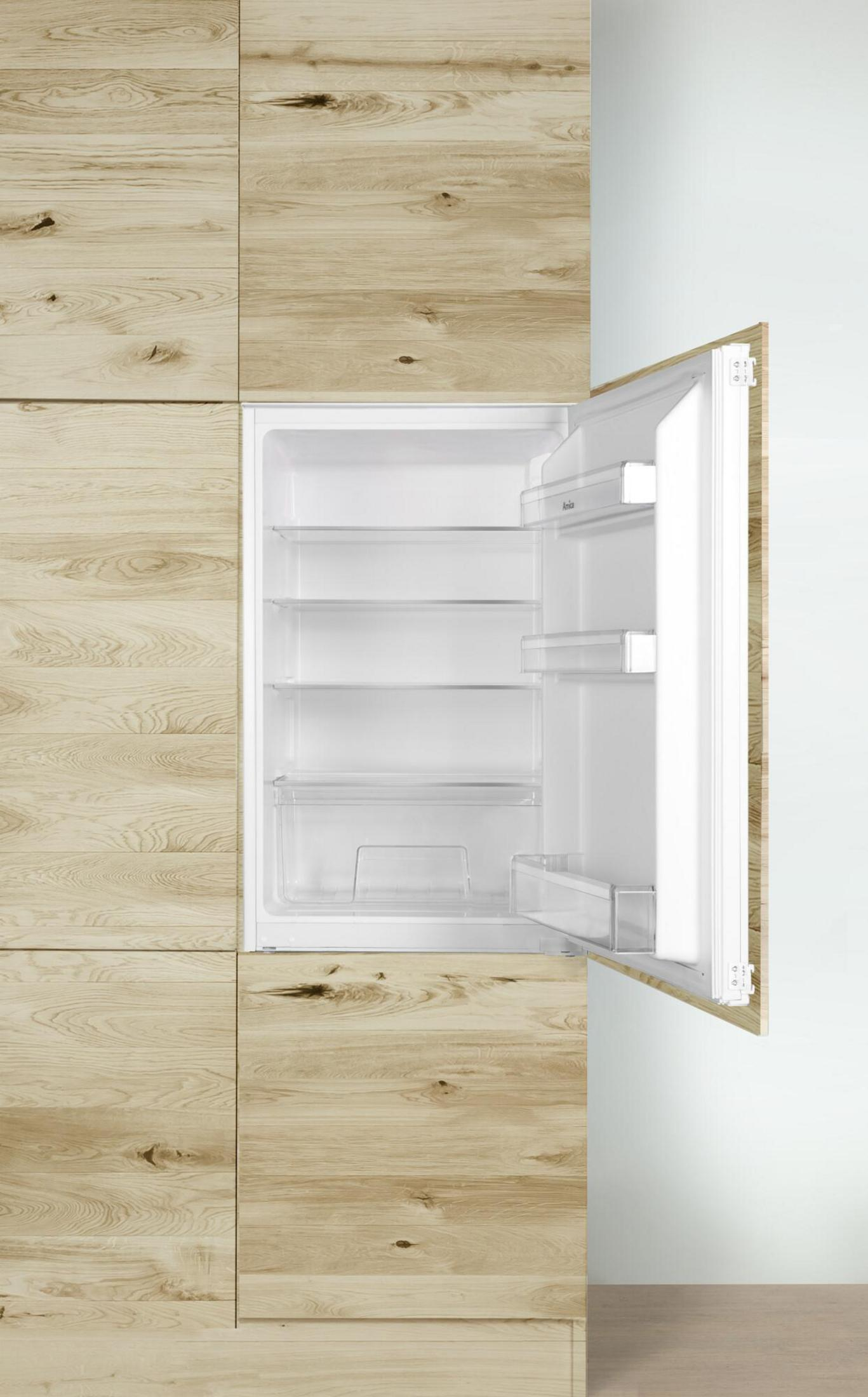 Ein kleiner offener Kühlschrank ist in Holzschränke eingebaut. Der Innenraum ist weiß mit durchsichtigen Regalen. Die Tür ist offen.