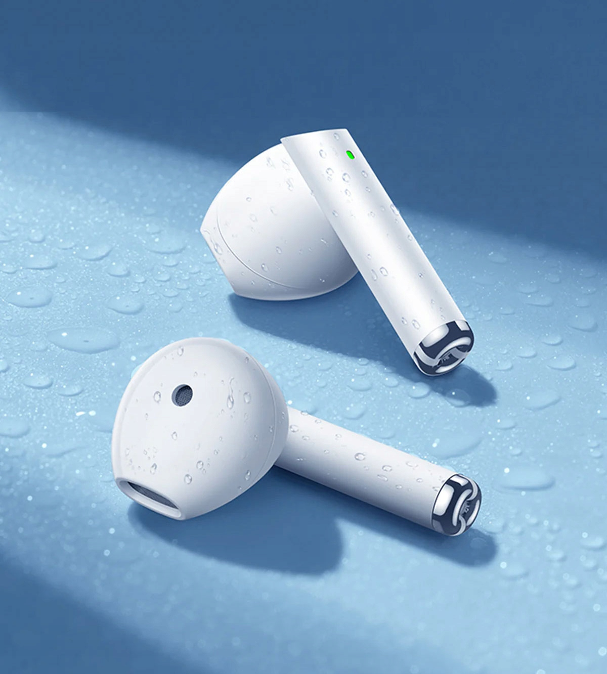 Due auricolari wireless bianche con dettagli argentati su una superficie blu con goccioline d'acqua.