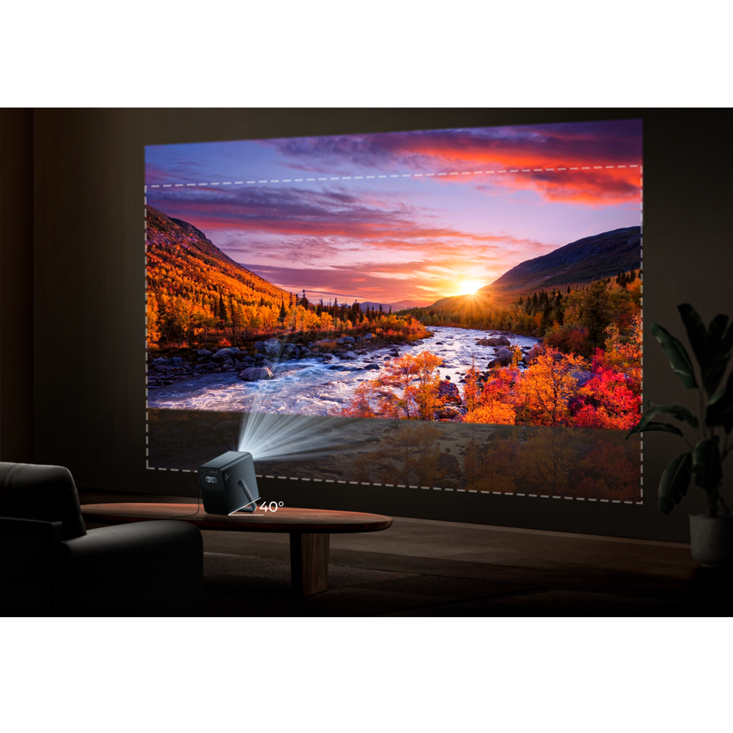 Ein Projektor zeigt eine Sonnenuntergangsszene mit Fluss und Bergen. Im Vordergrund sind Sofa, Tisch und Pflanze zu sehen.