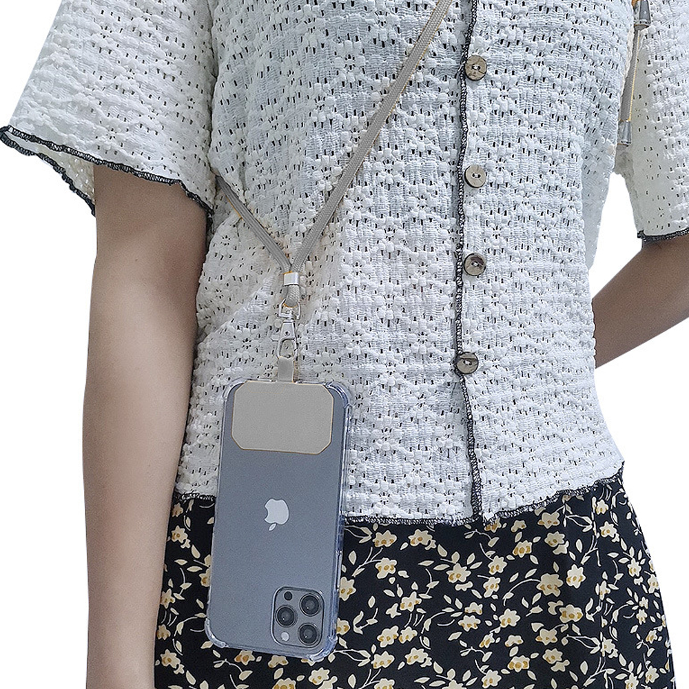 Eine Person trägt ein weißes Hemd und einen schwarzen Blumenrock. Ein Telefon mit grauem Gehäuse hängt an einem Halsband.