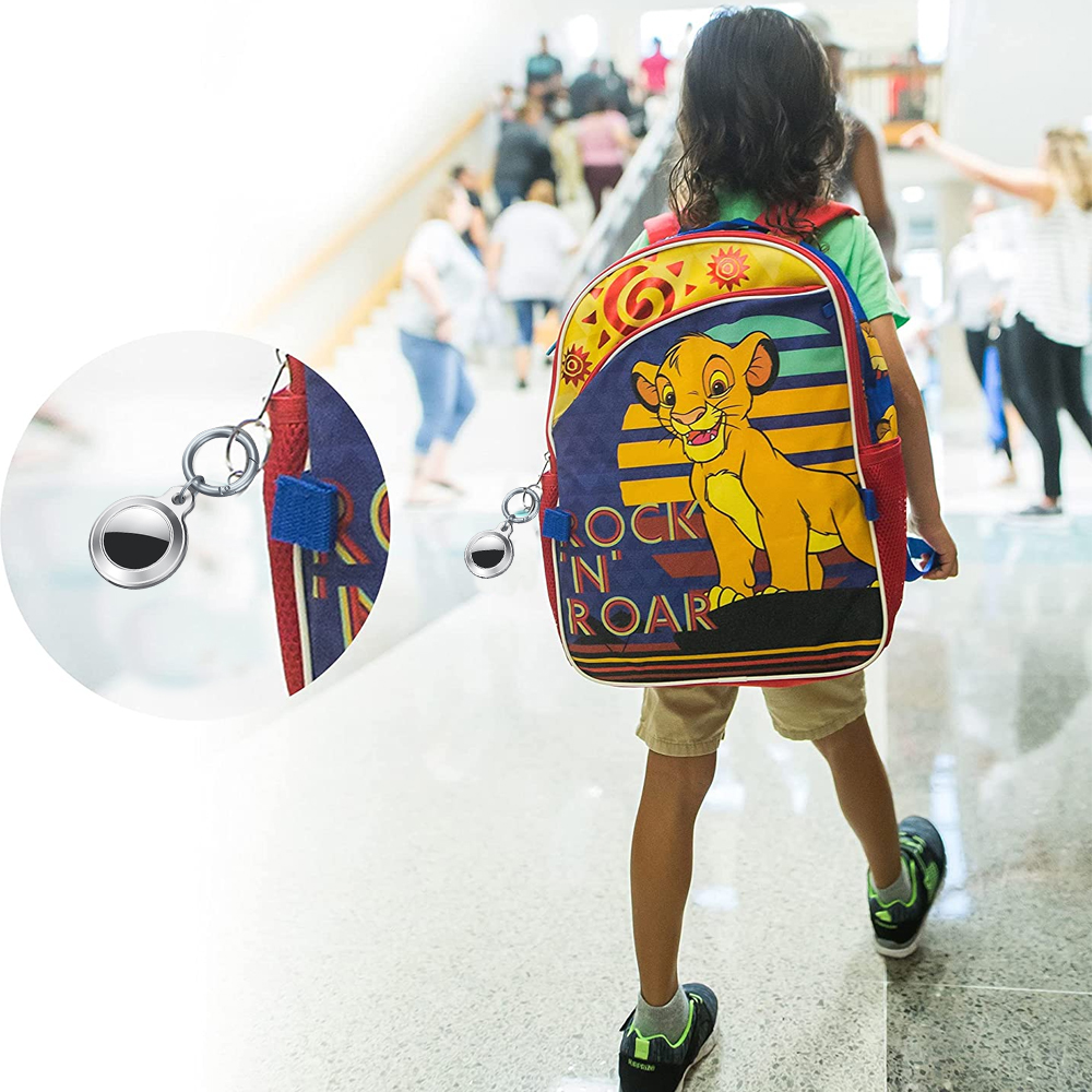 Ein Kind geht mit einem Rucksack mit Simba. Ein Metallanhänger ist befestigt. Andere Personen sind im unscharfen Hintergrund, in einem Schulflur.