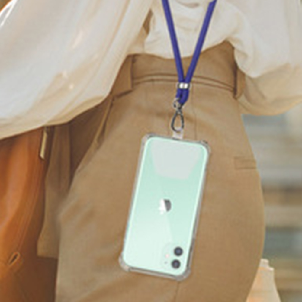 Der Oberkörper einer Person mit einem Telefon, das an einem blauen Schlüsselband hängt. Sie trägt ein cremefarbenes Hemd und eine beige Hose. Das Telefon ist mintgrün.