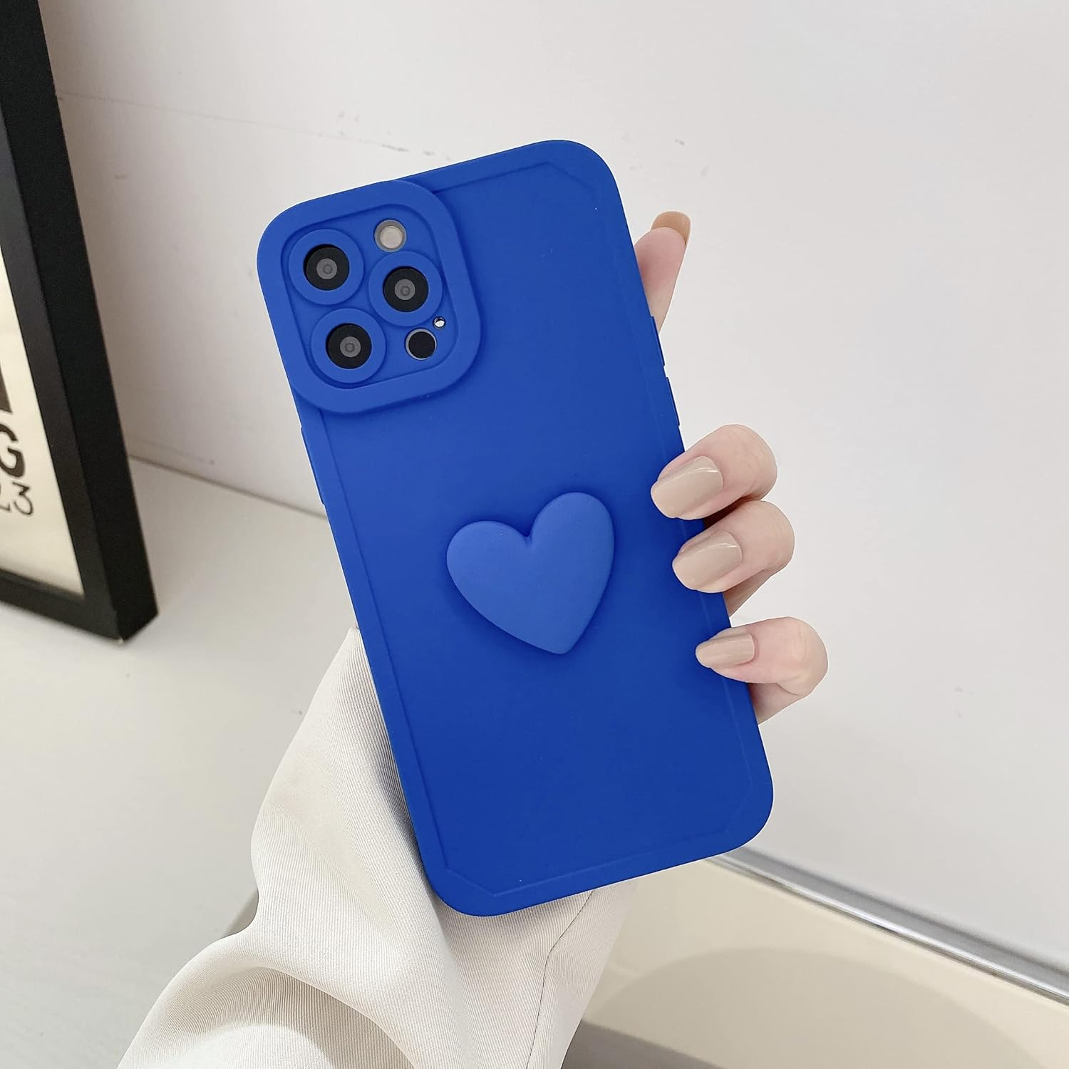 Eine Hand hält eine blaue Handyhülle mit Herz. Die Hülle bedeckt das Telefon mit Kamera und Herzmuster.