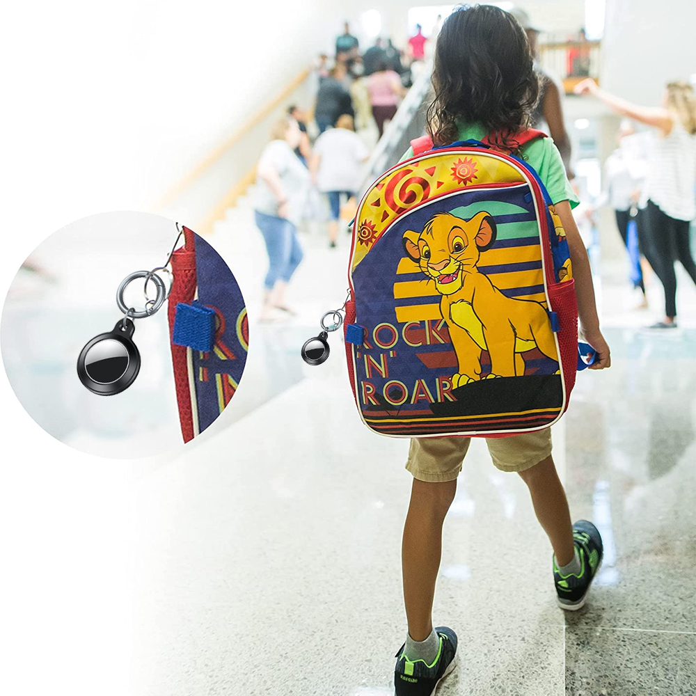 Ein Kind geht mit einem Rucksack mit Löwenbild. Ein schwarzer Tracker ist am Rucksack befestigt. Im Hintergrund sind Menschen zu sehen.