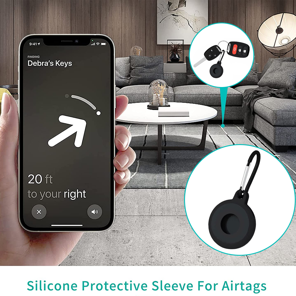 Hand, die ein Telefon hält, zeigt den Standort von 'Debra's Keys'. Schlüssel, schwarzer Airtag-Halter. Wohnzimmerhintergrund mit Sofa, Tisch und Lampe.