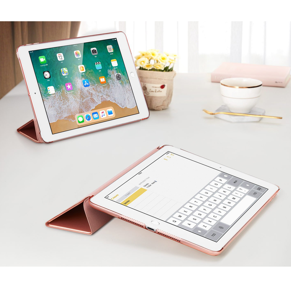 Zwei roségoldene iPads auf einem weißen Tisch. Eines ist hochgestellt und zeigt Apps. Das andere ist flach mit einer Tastatur.