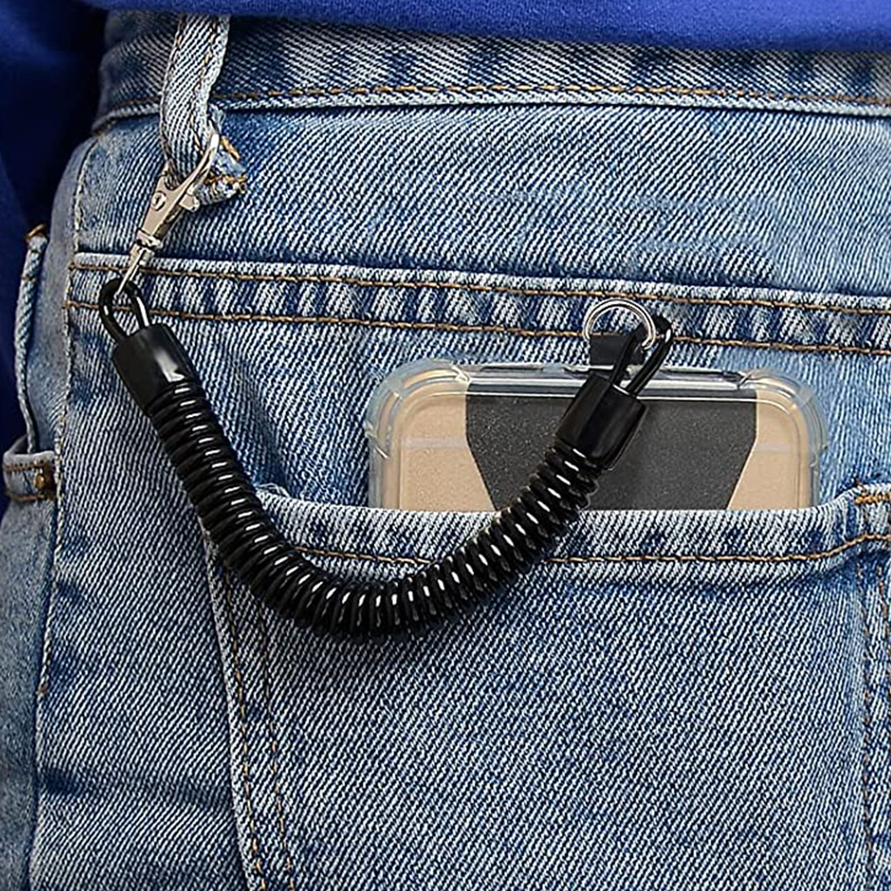 Nahaufnahme einer Jeanstasche mit einem Telefon in einer transparenten Hülle, befestigt an einem schwarzen Spirallanyard und einem Verschluss.