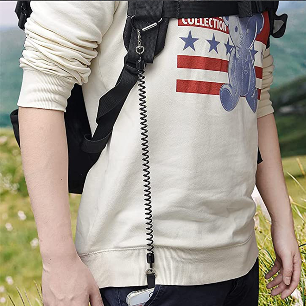 Eine Person mit Rucksack und Spiralschnur, die mit einem Telefon in der Tasche verbunden ist. Auf dem Hemd ist eine amerikanische Flagge und ein Bär zu sehen.