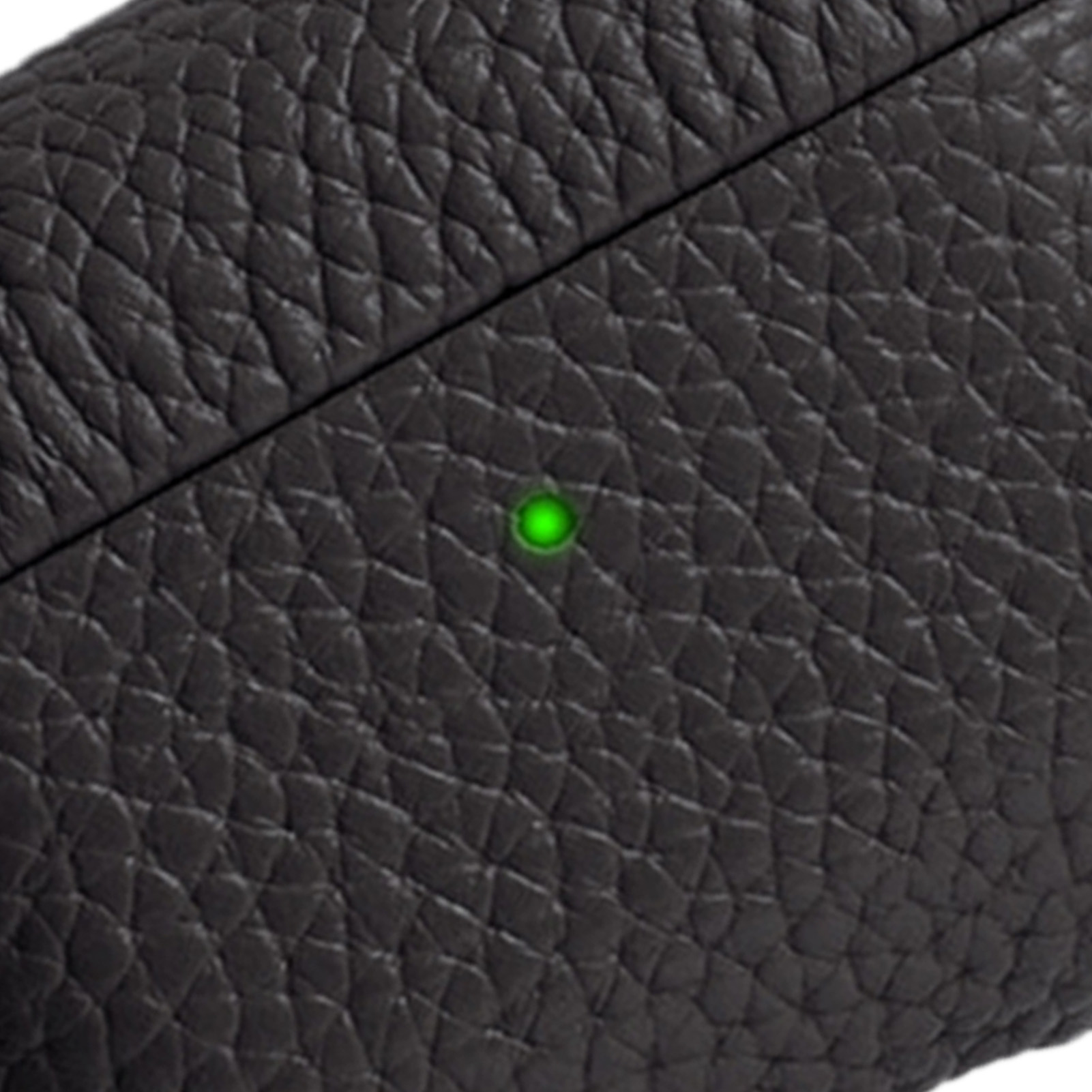 Nahaufnahme von schwarzem strukturiertem Leder mit diagonaler Naht. Ein kleines grünes Licht leuchtet auf der Lederoberfläche.