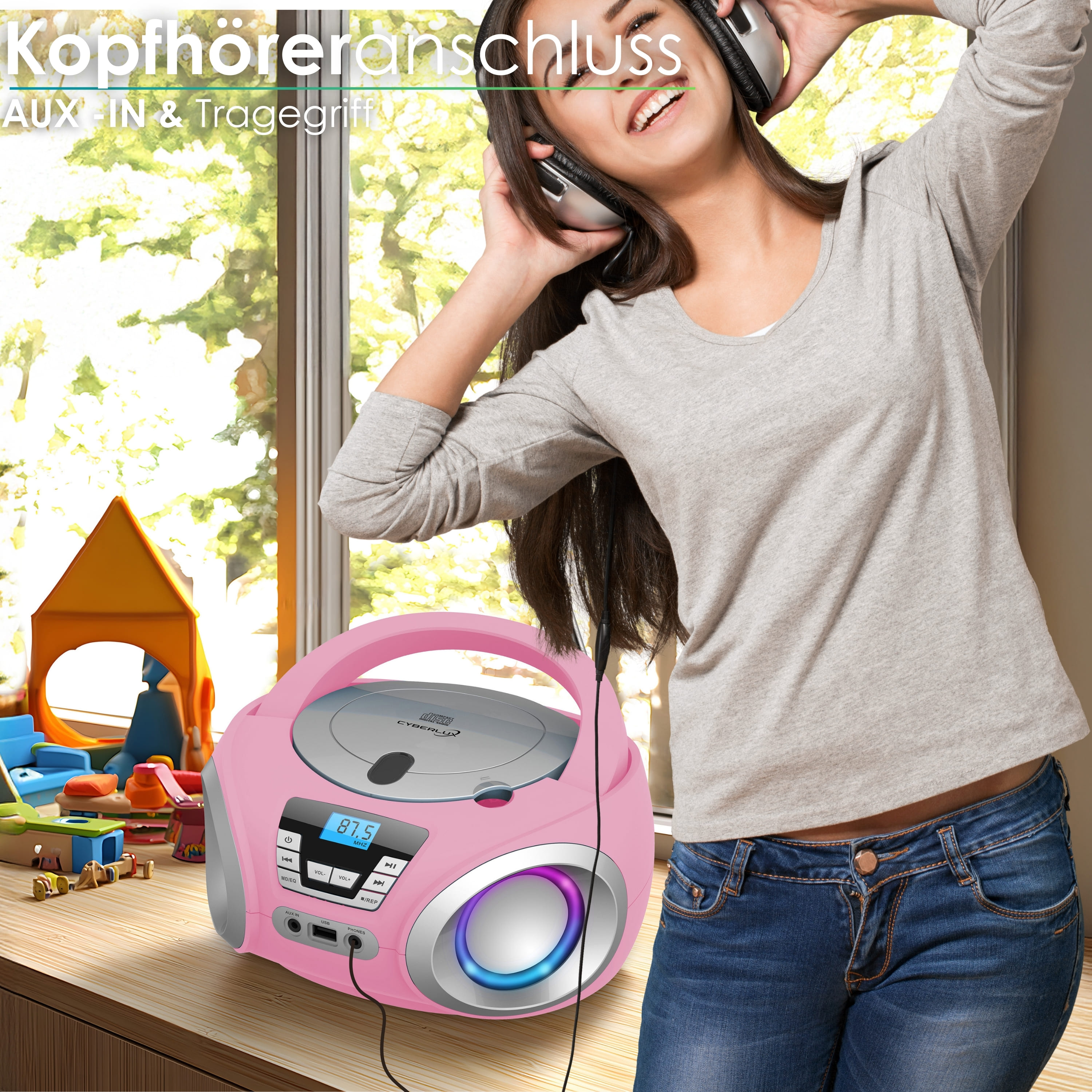 Eine Frau mit Kopfhörern lächelt neben einem rosa CD-Player. Im Hintergrund sind ein Fenster und Spielzeug zu sehen.
