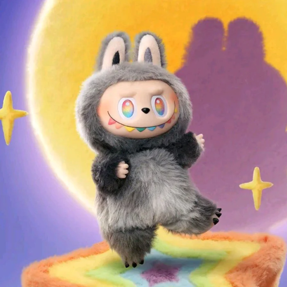 Eine Plüschfigur in einem grauen Hasenanzug mit bunten Augen und Zähnen steht auf einem Regenbogen-Teppich unter einem gelben Mond und Sternen.