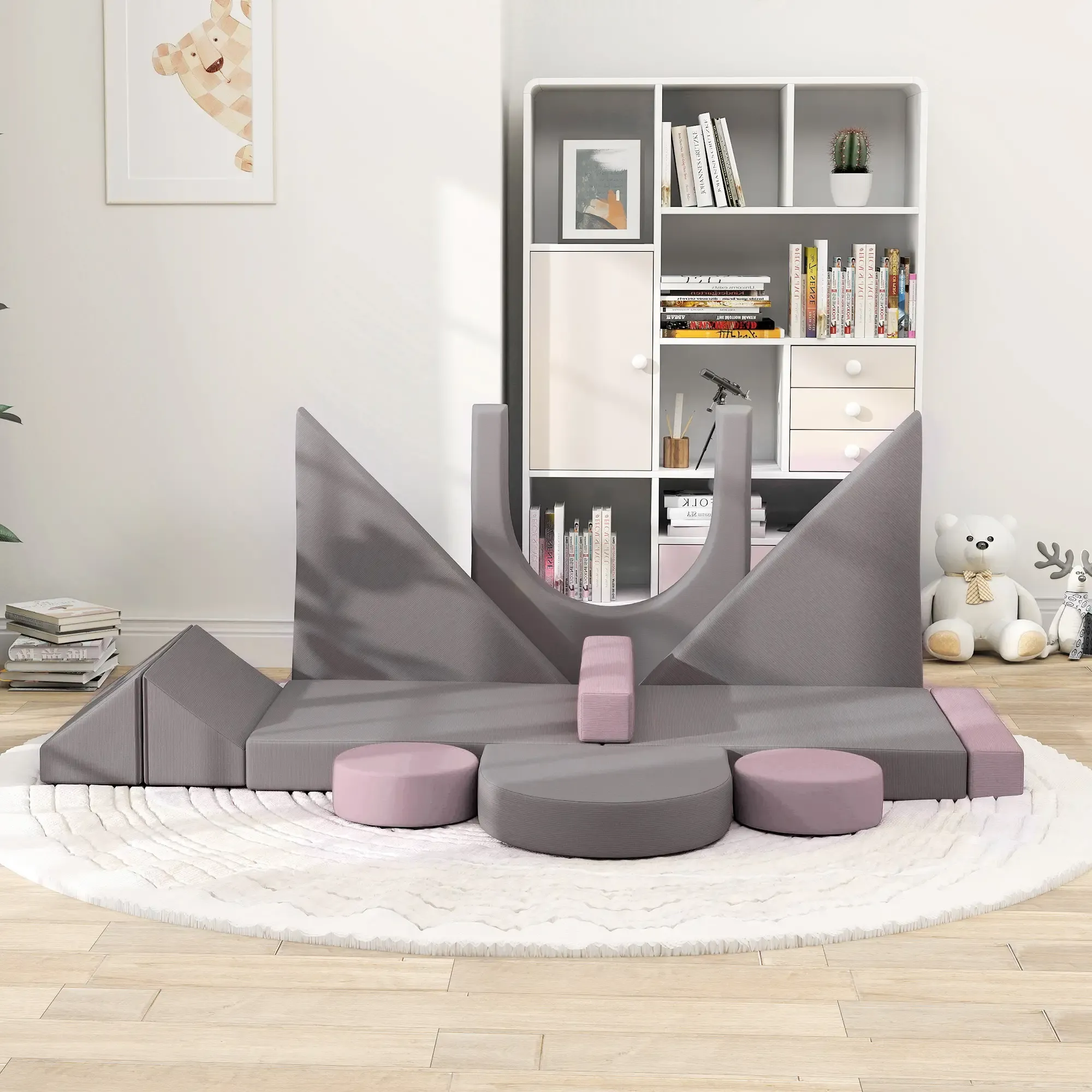 Ein Spielzimmer mit grau-rosa Spielstruktur, einem weißen Bücherregal mit Büchern und einem Teddybären.
