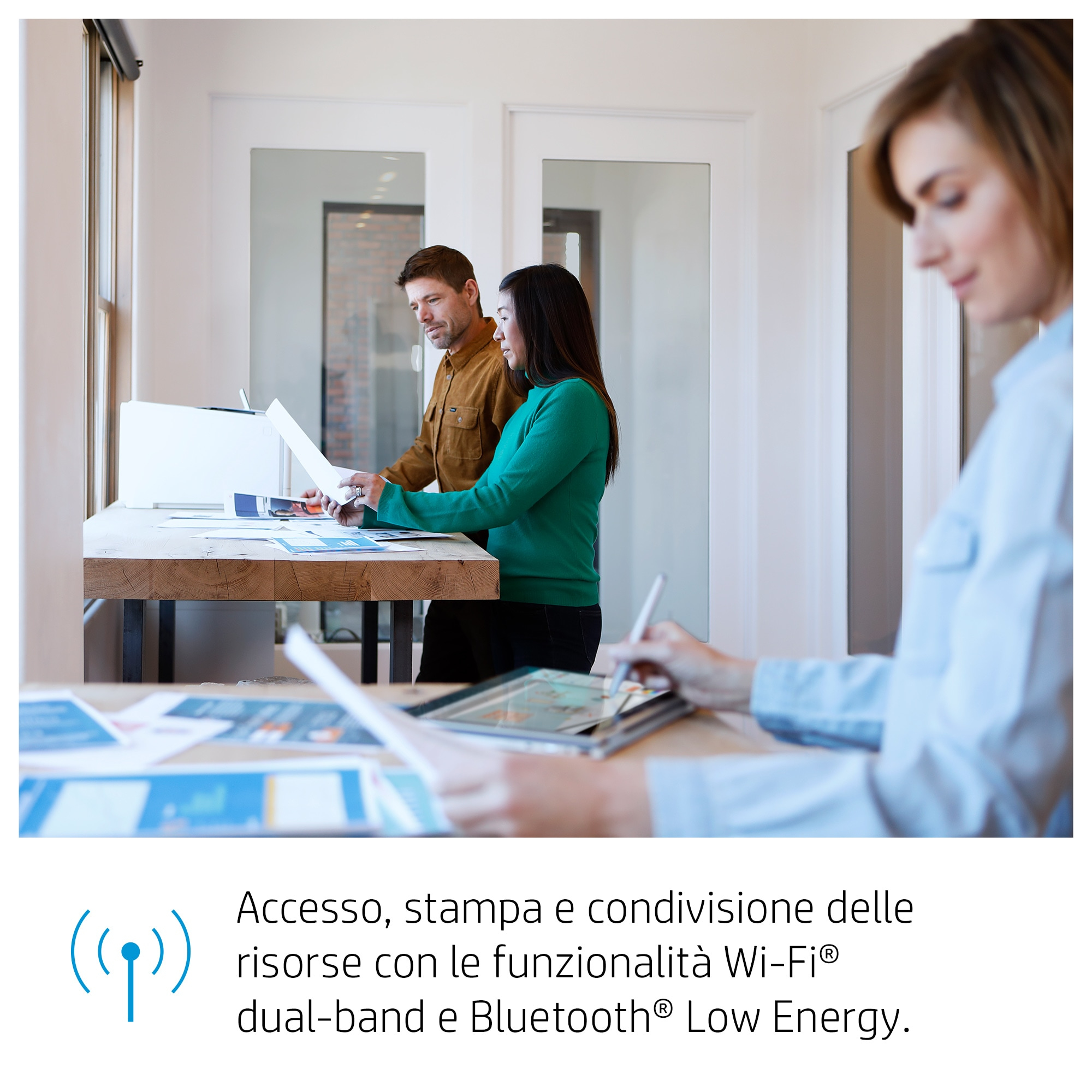 Tres personas en una oficina, mirando documentos y usando una tableta. Un logotipo de Wi-Fi es visible.