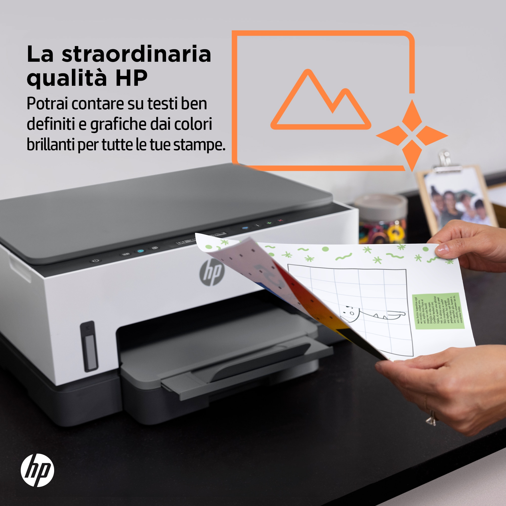 Una stampante HP stampa un foglio colorato. La scena comprende una grafica arancione, testo e mani che tengono la carta.