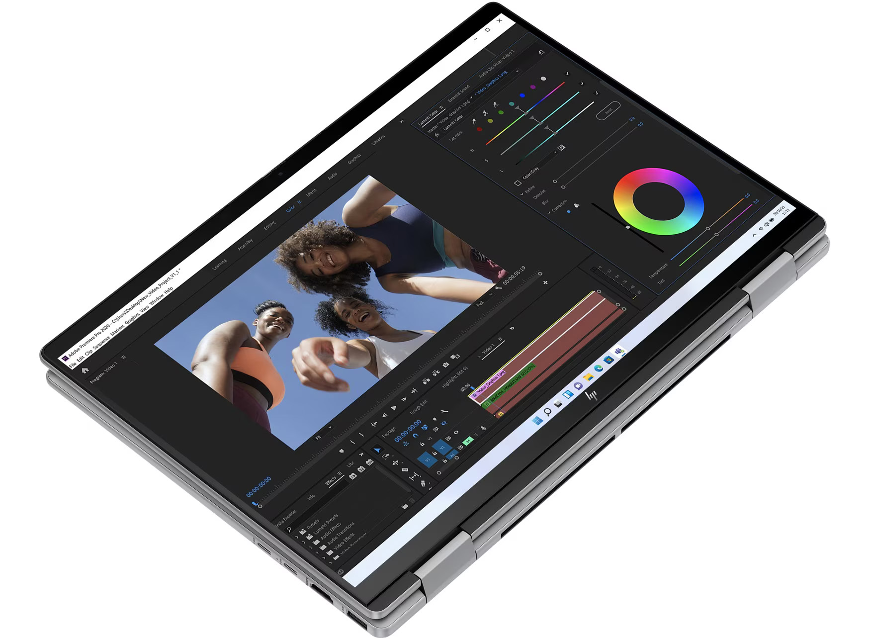 Laptop z oprogramowaniem do edycji wideo. Trzy osoby w tle, patrzące w dół. Widoczne elementy korekcji kolorów i oś czasu.