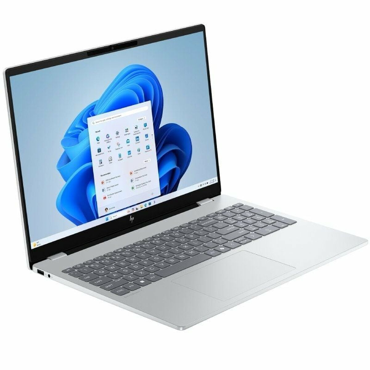 Laptop plateado con teclado gris y pantalla Windows 11 mostrando aplicaciones. La pantalla tiene un fondo de remolino azul.