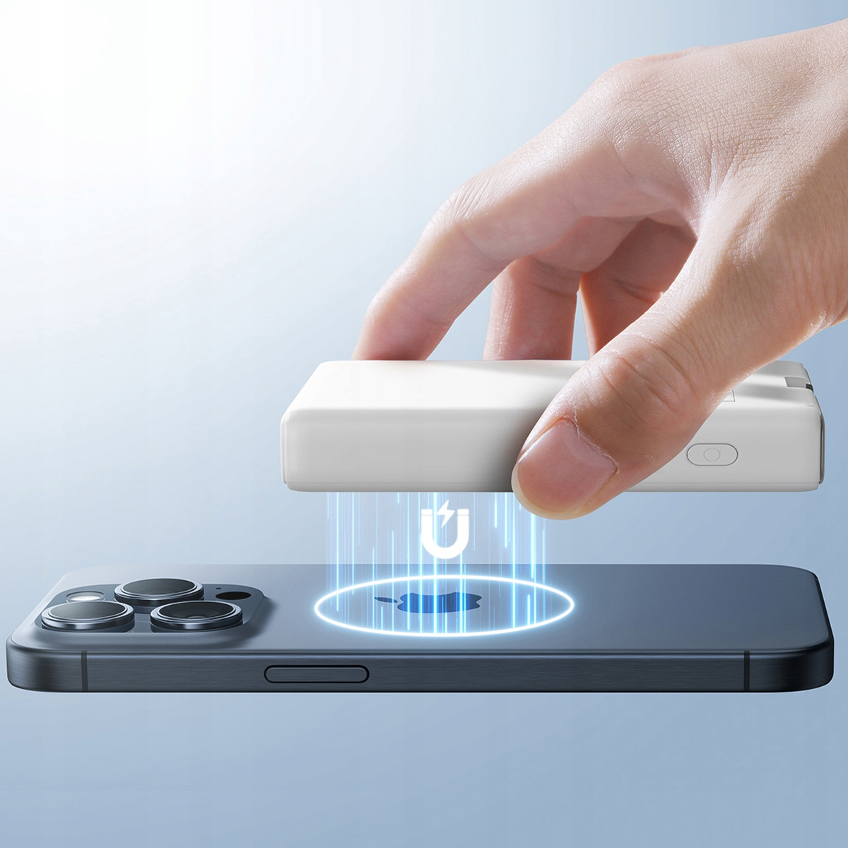 Ręka trzymająca biały power bank nad telefonem. Telefon ma symbol magnetyczny. Obecne są niebieskie linie.
