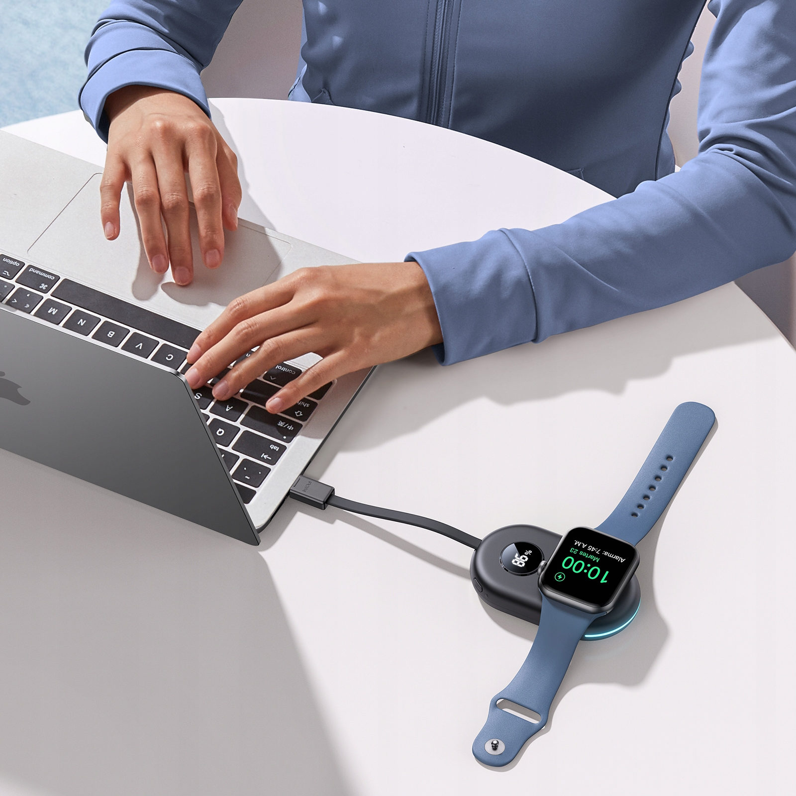 Kobieta używająca laptopa ze smartwatchem ładującym się na bezprzewodowej podkładce ładującej.